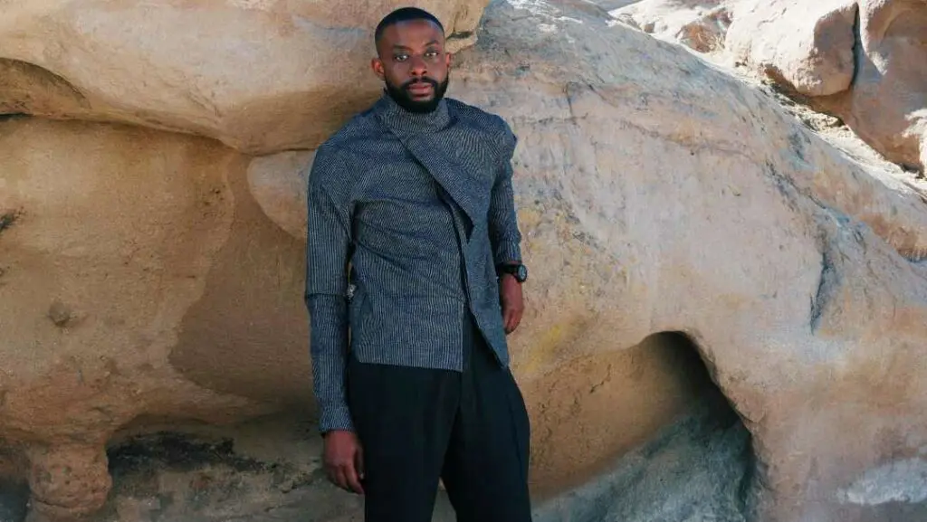 John e Imah, con indosso una giacca testurizzata, posano davanti a una formazione rocciosa