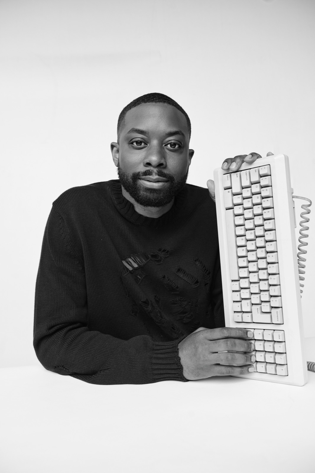 Black-and-white portrait of John Imah holding a vintage keyboard
