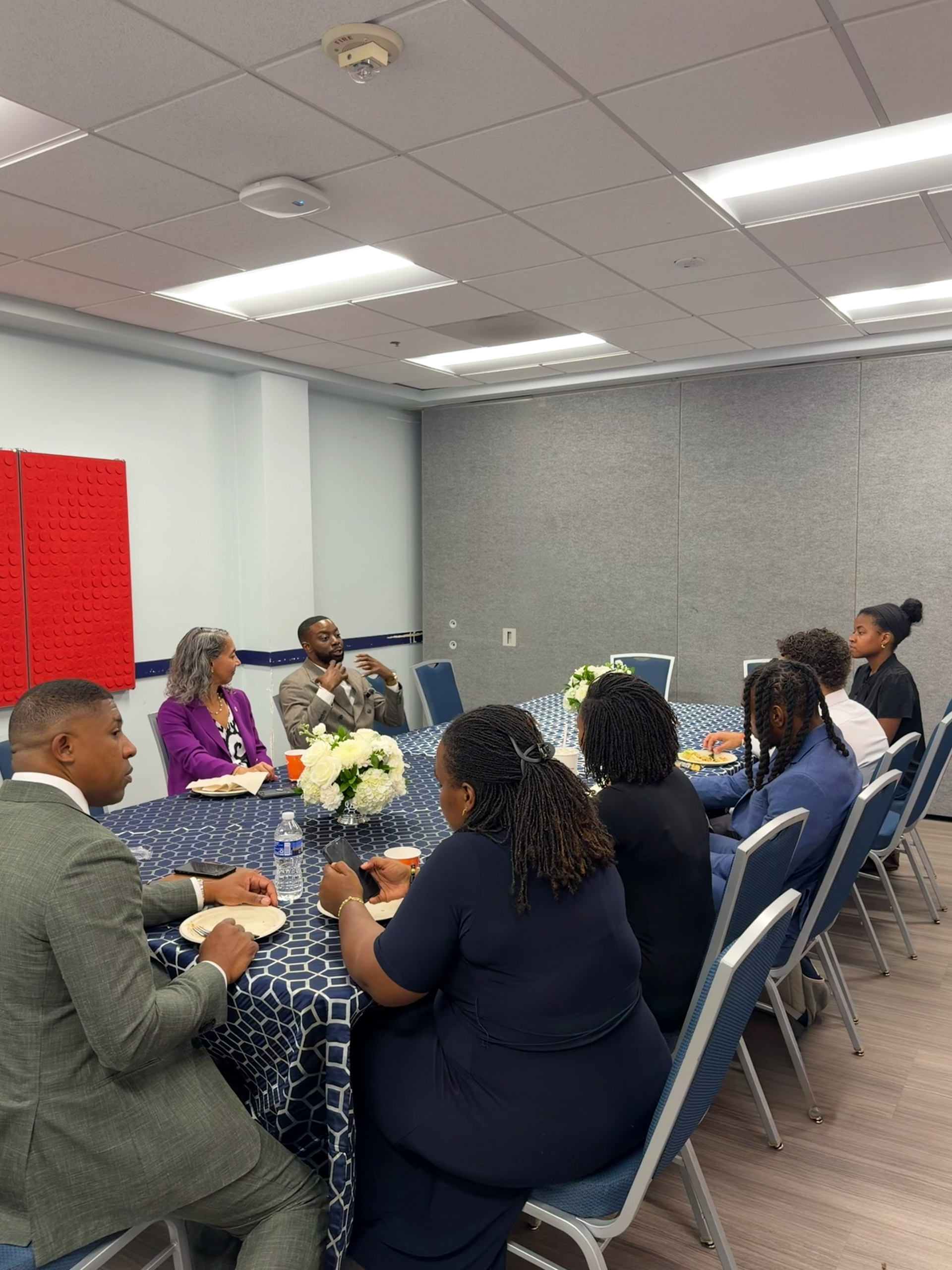 John Imah speaking with a group seated around a table during his visit to Howard University.
