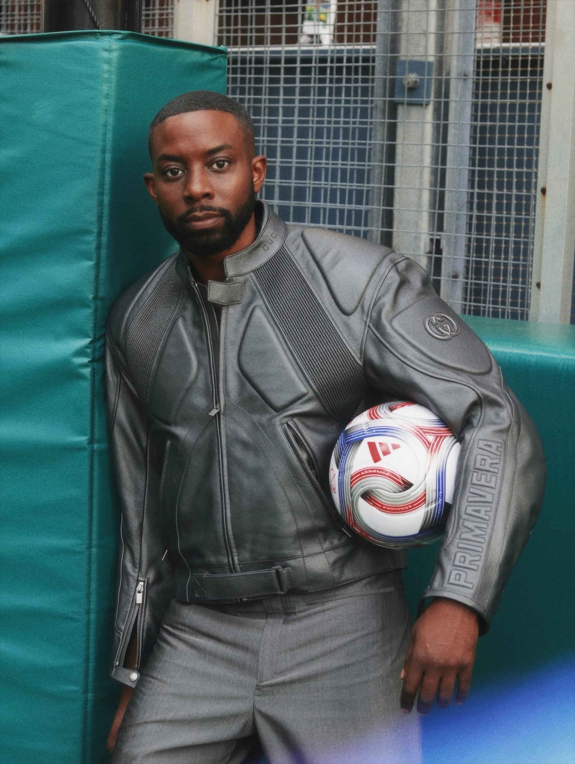 John Imah holding a soccer ball in a gray jacket